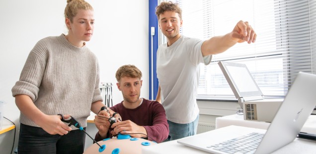 Studenten, die gerade operative Techniken an der Laparoskopie-Box, die den Bauchraum simuliert, trainieren