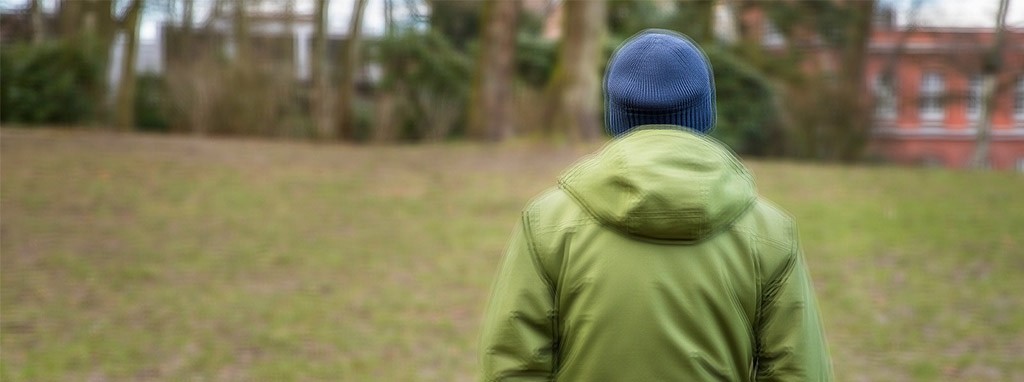 Bildbeispiel für die Erkrankung Depression - ein  Mann von hinten auf einer Wiese fotografiert