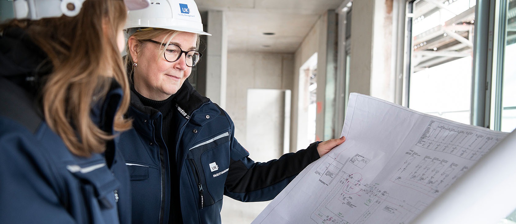 Two colleagues discuss the construction plan on a building site